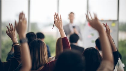 People raising their hands in a presentation