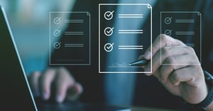Hand signing a digital document on a virtual checklist display above a laptop